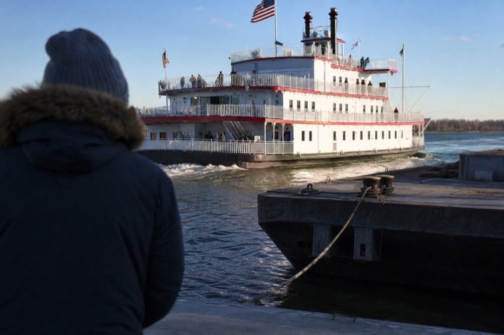 Large multi-deck paddlewheel riverboat cruising past the Savannah riverfront, no text, no logos, no people