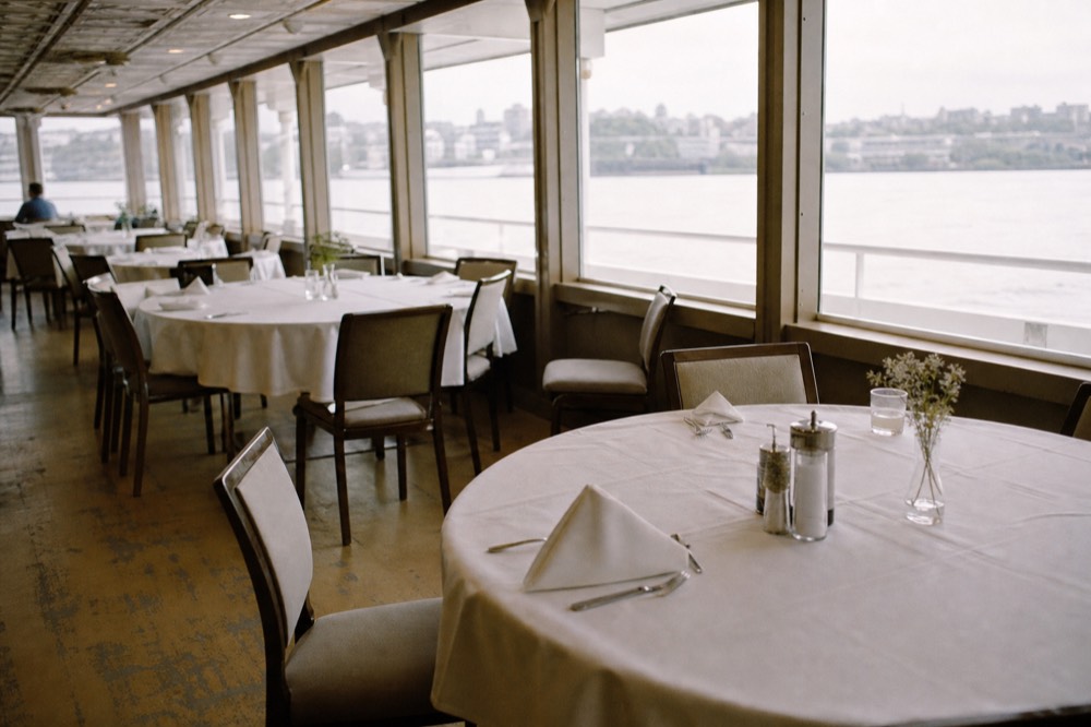 Interior dining deck of a riverboat set with tables near large windows, no text, no logos, no people