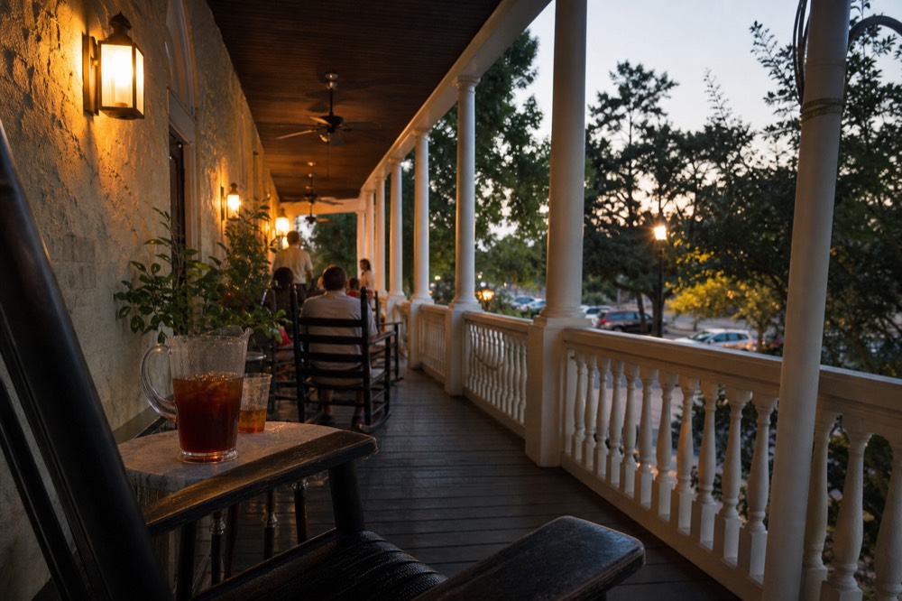 Warm lamplight on a historic hotel porch in Savannah in the evening, no text, no logos, no people