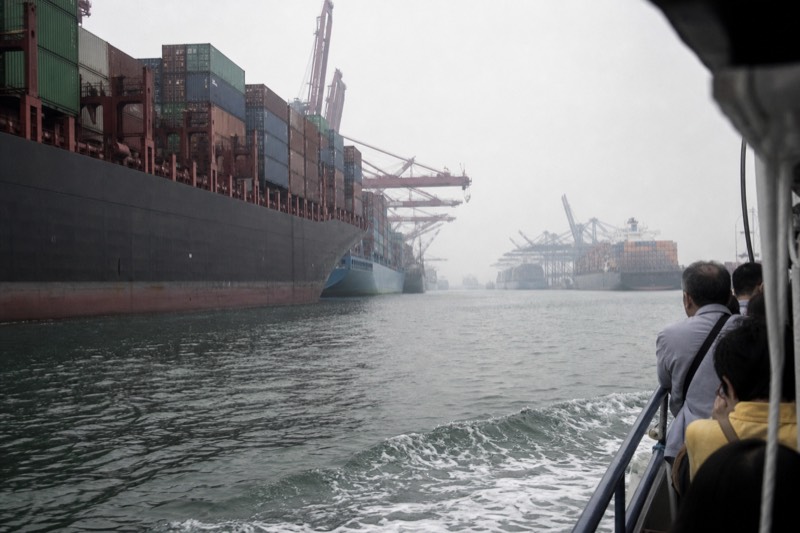 A tour boat passing container ships and cargo cranes on the working stretch of the Savannah River