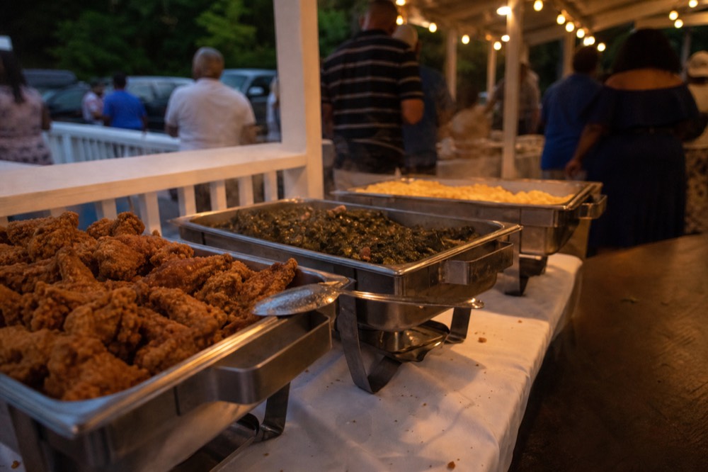 Southern buffet table with fried chicken and sides under warm deck lighting, no text, no logos, no people
