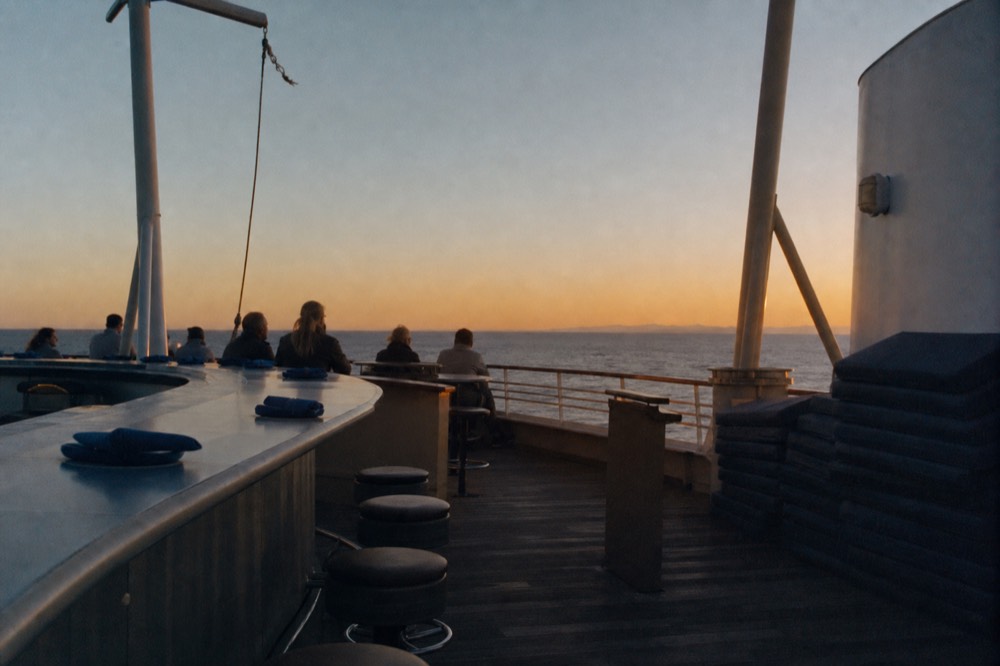 Open-air upper deck of a paddlewheel riverboat at dusk, no text, no logos, no people