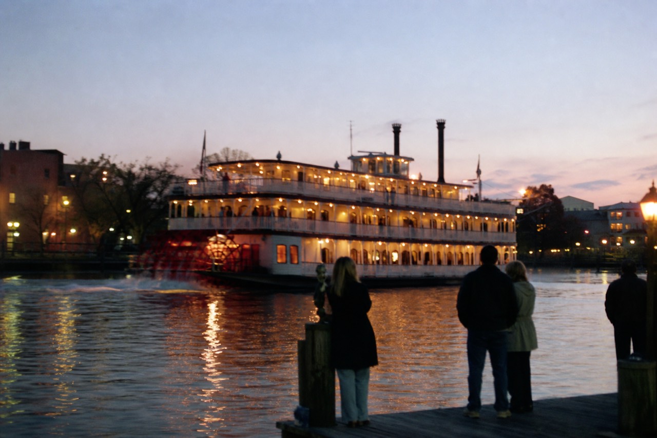 Paddlewheel riverboat lit at dusk on the Savannah River, no text, no logos, no people