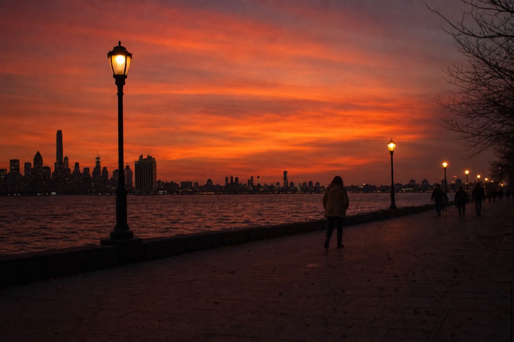 Savannah riverfront skyline under a deep orange sunset sky, no text, no logos, no people