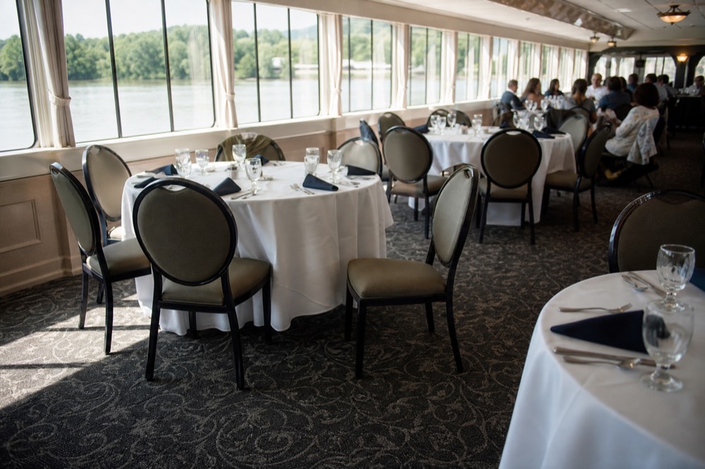 A brightly lit riverboat dining room with tables set for a daytime meal, no text, no logos, no people