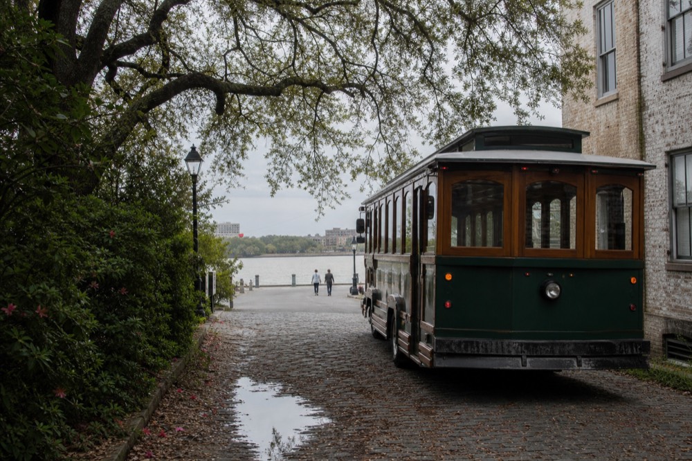 Historic trolley on a Savannah street beside the riverfront, no text, no logos, no people
