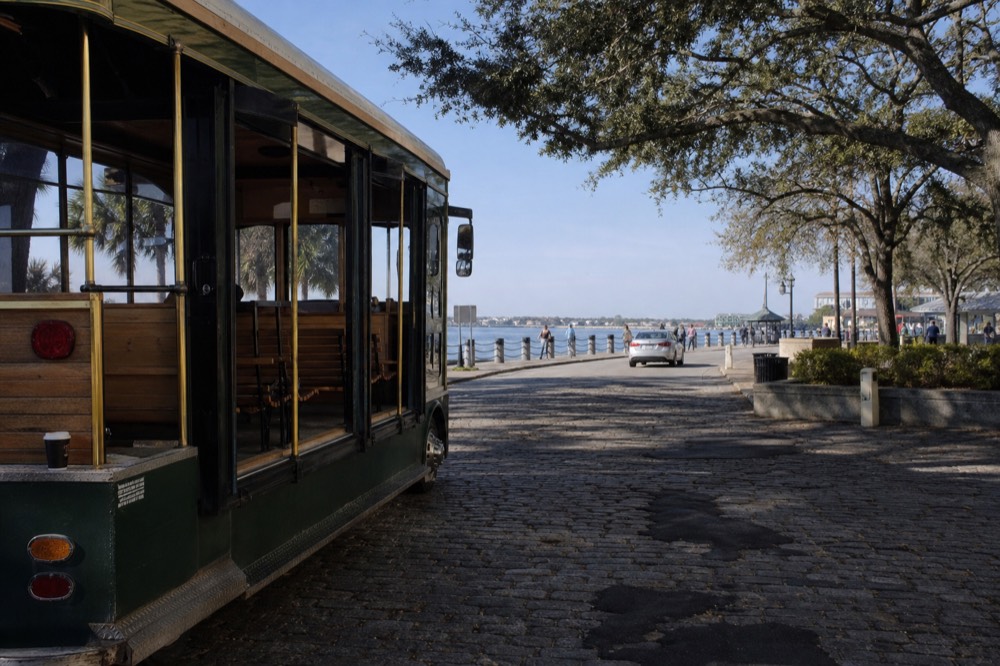 A hop-on-hop-off trolley parked near the Savannah riverfront, no text, no logos, no people