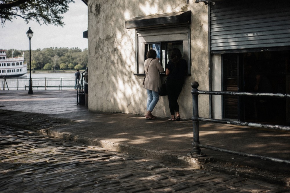 A riverboat ticket window on River Street with cobblestones in the foreground, no text, no logos, no people
