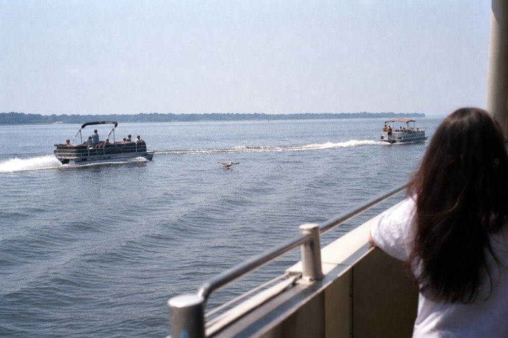 Two riverboats passing on a wide coastal river at midday, no text, no logos, no people