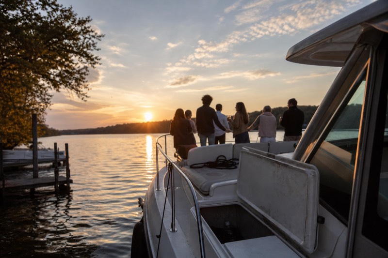 A small private charter boat idling on the Savannah River near the Hutchinson Island shoreline at golden hour, departing near the Savannah Convention Center on the river's north bank