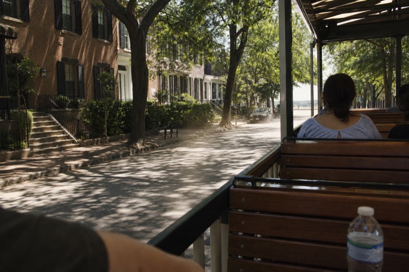 A riverboat docked on River Street beside a historic trolley on the cobblestone waterfront in Savannah, near the Savannah Visitors Center on Martin Luther King Jr Boulevard
